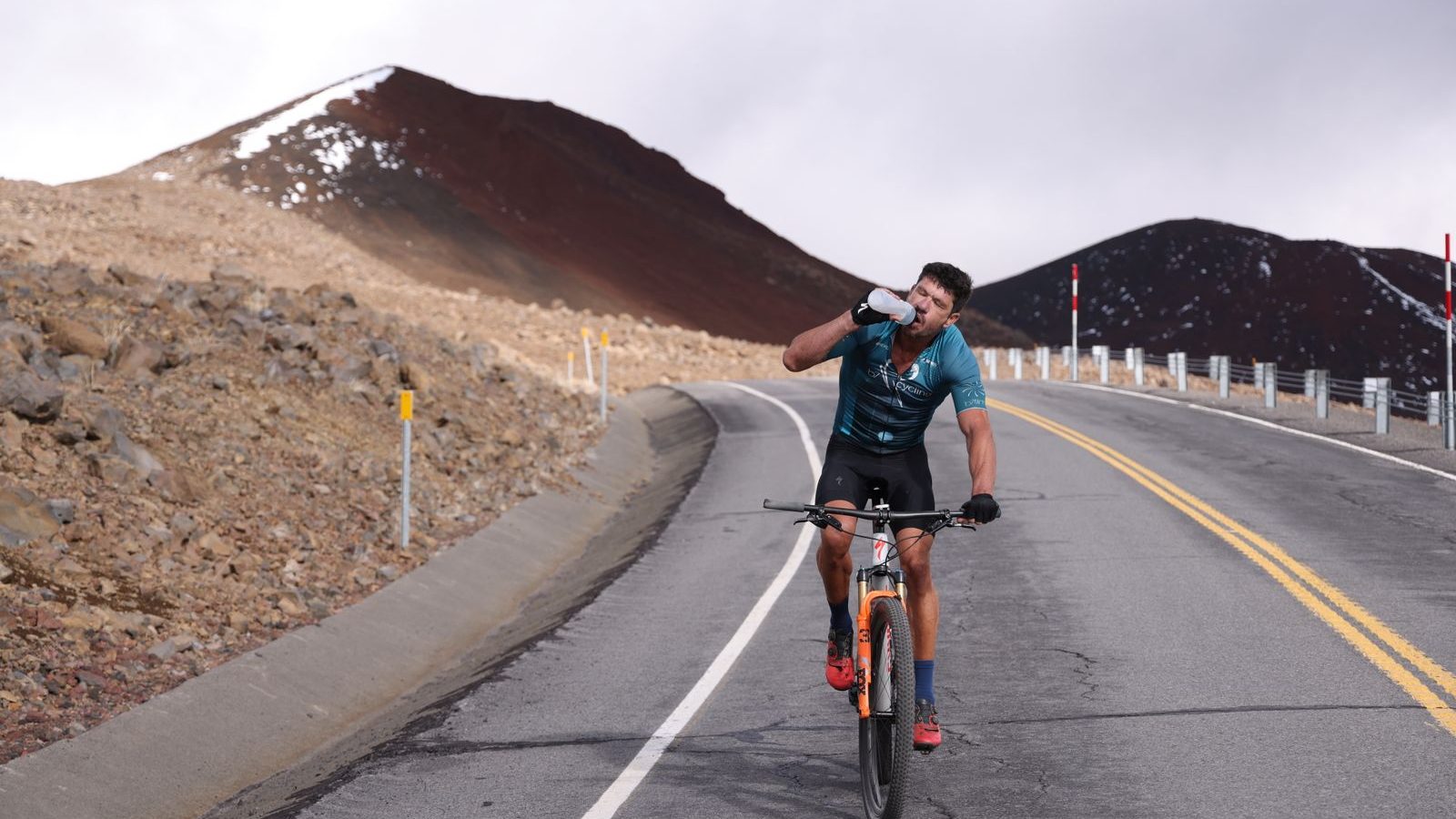 Cycliste buvant au bidon sur une route de montagne pendant une sortie d'endurance