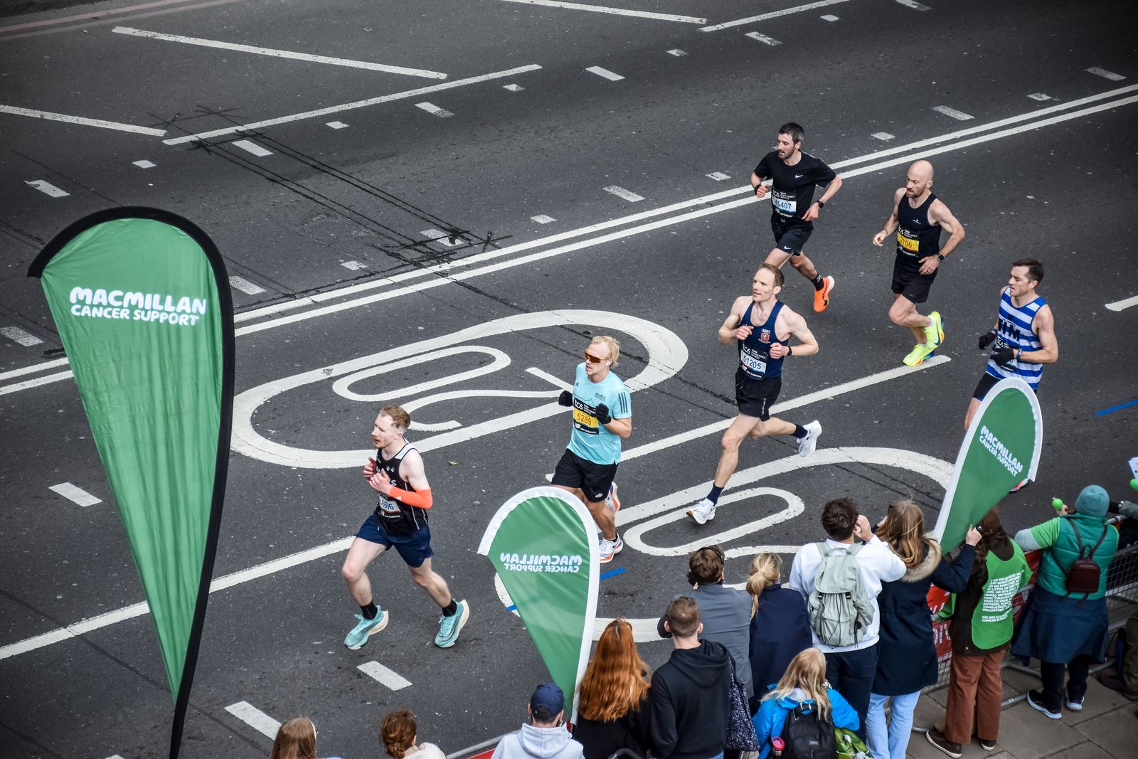 Groupe de marathoniens sur un parcours urbain bordé de spectateurs