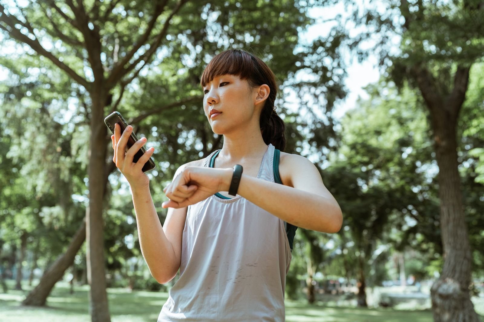 Coureuse consultant son téléphone et son bracelet d'activité après une séance